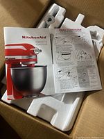 User manual showing KitchenAid model numbers KSM3311X and KSM3316X inside packaging