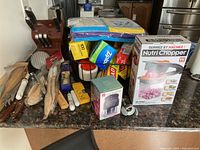 Wide view of the kitchenware items on countertop showing utensils, knife block, cleaning cloths, boxes of food wrap, and Nutri Chopper