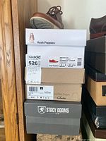 Stacked shoe boxes showing Hush Puppies, Clarks Collection and Stacy Adams branding.