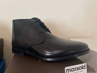 Single black leather chukka boot on box