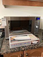 Front angle of Panasonic inverter microwave and boxed CorningWare Platinum Oblong Baker on granite countertop.