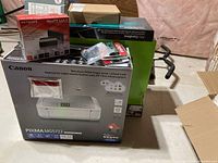 Photo of boxed Canon Pixma MG5722 all-in-one printer with other tech items around