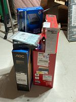 Stack of boxed items including Sabrient hard drive enclosure, Megadisk external hard drive, Canon printer box, AOC monitor box, MX3 TV box.