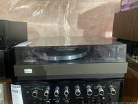 Front view of Sansui turntable on top of amplifier under clear dust cover