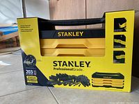 Front view of the unopened Stanley Professional Grade 3-drawer toolbox chest with mechanics tool set in yellow and black packaging.