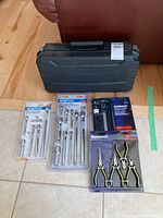 Mastercraft tools displayed on floor: several extension bar sets in packaging, pliers set in packaging, electronic caliper and rotozazer saw case.