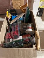 Box of assorted tools including saws, wrenches, brushes, and plumbing parts.