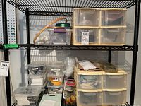 Two shelves filled with plastic storage drawers and various craft supplies including wood embroidery hoops, plastic bags of tools, and smaller containers with ribbons and hardware.