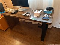 Full front view of desk showing wood top and metal leg with items placed on top (items not included).