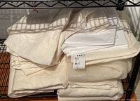 Folded felt fabric and stacked white sheets on a black metal shelf.