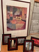 Paul Klee framed poster and five smaller framed NYC photographs on floor near wall.