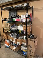 Front view of shelving unit filled with assorted boxes, paint cans, tools, and miscellaneous items