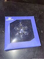 Full view of Swarovski blue box with snowflake crystal ornament inside visible through clear window.