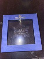 Blue textured Swarovski box with transparent window displaying a crystal snowflake ornament inside.