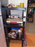 Shelf unit with various toys including Monopoly board game, puzzles, balls, and stuffed animals