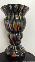 Full view of bulbed, multicolored striped art glass vase with flared rim.