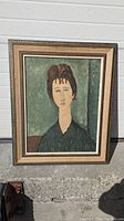 Frontal view of framed art print depicting a Modigliani-style portrait of a woman in muted green and brown colors.