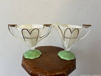 Front view of both cream and sugar set showing white glass bodies with brown geometric design and green footed base.