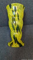 Side view of yellow and green spatter glass vase showing shape and color pattern