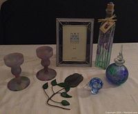 Full lot of art glass pieces including candle holders, frame, rose, kiwi bird, perfume bottle, and small bird figurine on white cloth