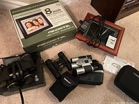 Lot group including brown wood-framed digital photo frame with remote and charger, black Tasco binoculars, Vivitar silver/black binoculars, Bose headphones, and other binoculars