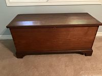 Front view of a polished solid wood blanket box showing rectangular shape and keyhole lock on lid.