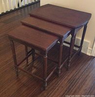 Set of three wooden nesting tables stacked together showing their size differences and condition.