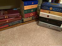 Stack of Diana Gabaldon fiction books arranged showing titles and author's name including various Outlander series novels.