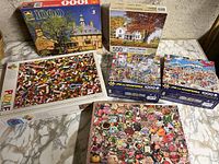 Six jigsaw puzzle boxes displayed on marble surface showing various sizes and themes.