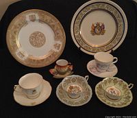 Lot showing 2 plates with royal family motifs and 5 assorted royal crest tea cup and saucer sets on black background