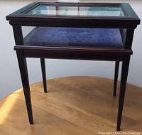 Front angled view of the shadow box table showing dark wood frame, glass top and blue plush interior mat.