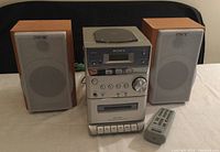 Full view of Sony Micro Hi-Fi Component System including main stereo unit, two wooden speakers, and remote control placed on table.