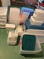 Large assortment of clear and colored plastic storage totes and bins arranged on basement floor.
