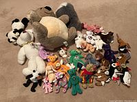 Overview photo showing a large collection of assorted Beanie Babies including bears, koala, panda, birds and other animals spread on floor