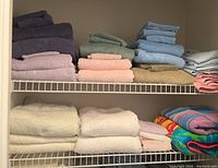 Shelves with folded towels in purple, green, blue, pink, beige, white, and multicolor beach towels.