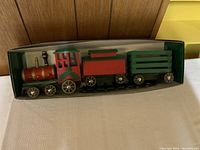 Front angle view of wooden Christmas train set in box showing locomotive and cars
