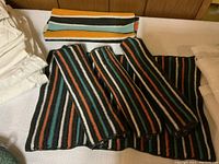 Photo showing sets of striped knitted tea towels and tea cozies in multiple colors.