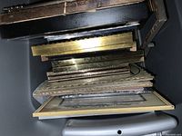 Stack of assorted old picture frames including brass and wood, laid horizontally.