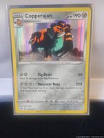Front view of a holographic Copperajah Pokemon card showing detailed attack stats and artwork.