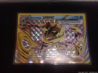 Close-up image of Greninja BREAK Full Art Holo Pokemon card showing detailed gold and blue holographic foil with attack, health, and ability text.