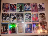 Photo showing 18 assorted sports cards, mostly hockey, some with holographic foil effects and various team uniforms.