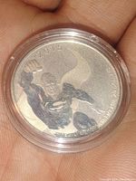 Close-up photo of a 2015 Canadian silver coin featuring Superman design in an individual's hand. The coin is housed in a clear protective capsule.