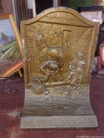 Front view showing detailed relief cast scene of a blacksmith shop with figures and inscription.