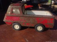 Side view of vintage Tonka toy truck showing worn red and gray paint and white wheels.