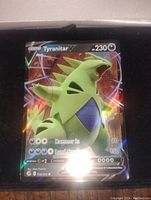 Full view of Tyranitar V full art holo foil Pokemon card in a protective sleeve showing holographic effects and artwork.