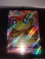Full art holographic foil Victini V-Max Pokémon card shown clearly displaying the front with shiny reflective surface and attacks visible.