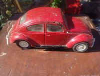 Side view of vintage red Tonka metal Volkswagen Beetle toy car showing condition and details.