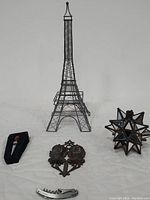 Metal Parisian Eiffel Tower centerpiece, vintage 12 point mirrored Moravian star candleholder, antique cast iron match holder wall pocket, Wine Country Connoisseur's Collection bottle stopper, and turtle nose stainless steel bottle opener all displayed together on a white surface.