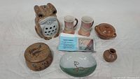 Overview of all stoneware pieces including frog candleholder, Sharon Hubbard mugs, and other stoneware items
