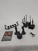 Black-toned decorative items arranged on a white cloth, showing all items in the lot including candleholder, plaque, bookends, bull sculpture, candlesticks, and vase.